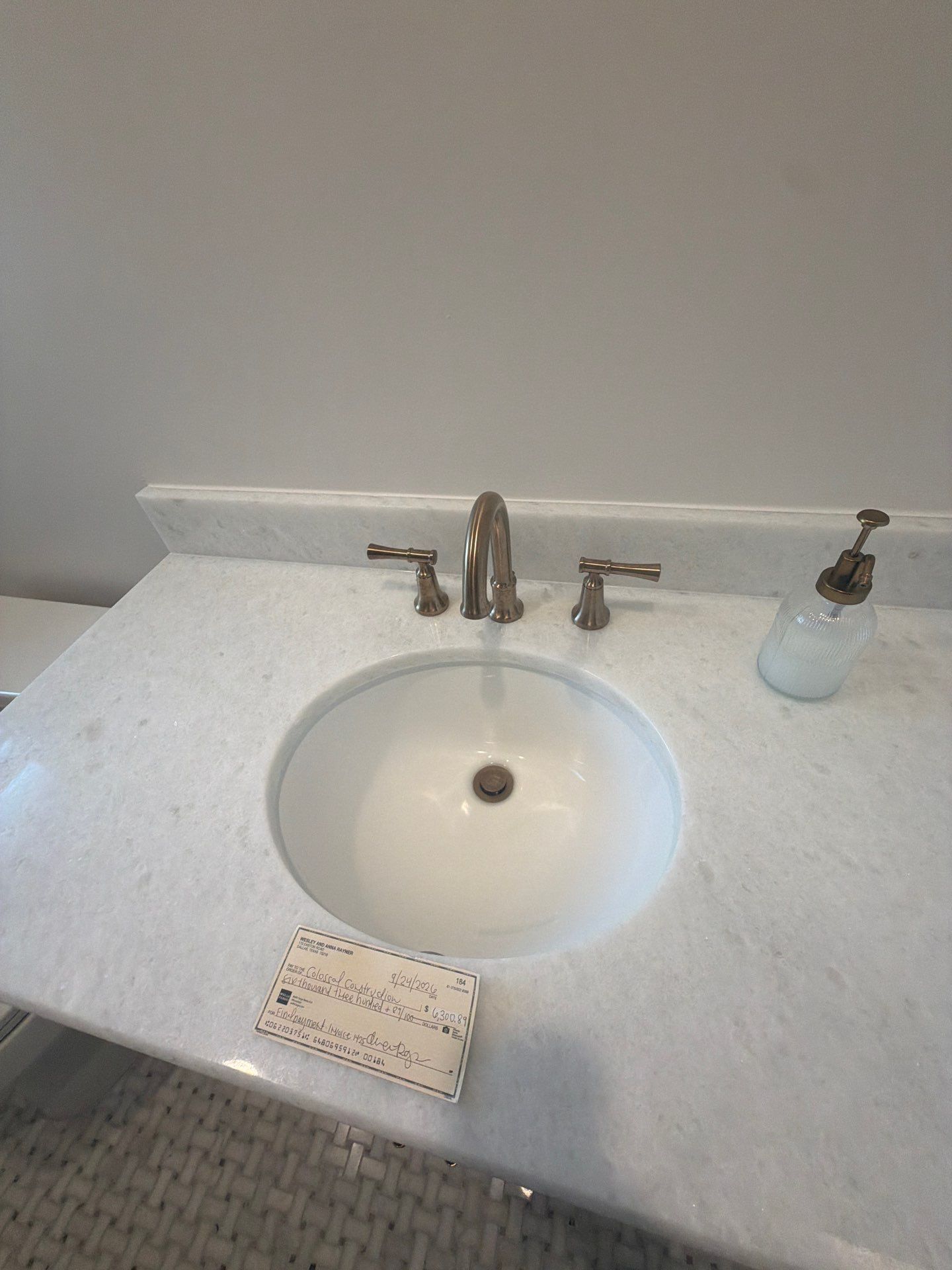 White bathroom sink with chrome faucet, soap dispenser, and a small sign on the counter.