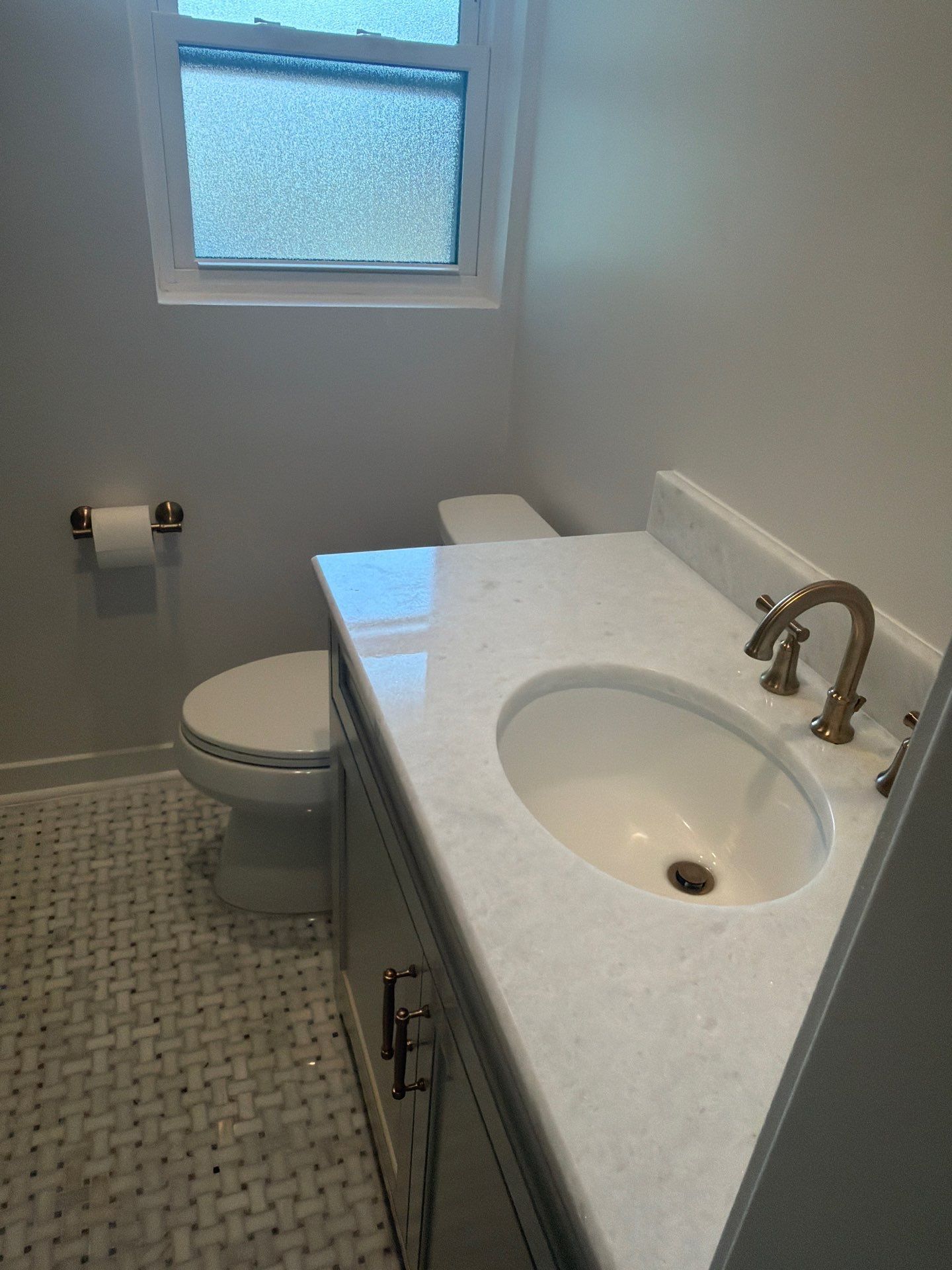 Small bathroom with toilet, vanity sink, and frosted window, viewed from the doorway