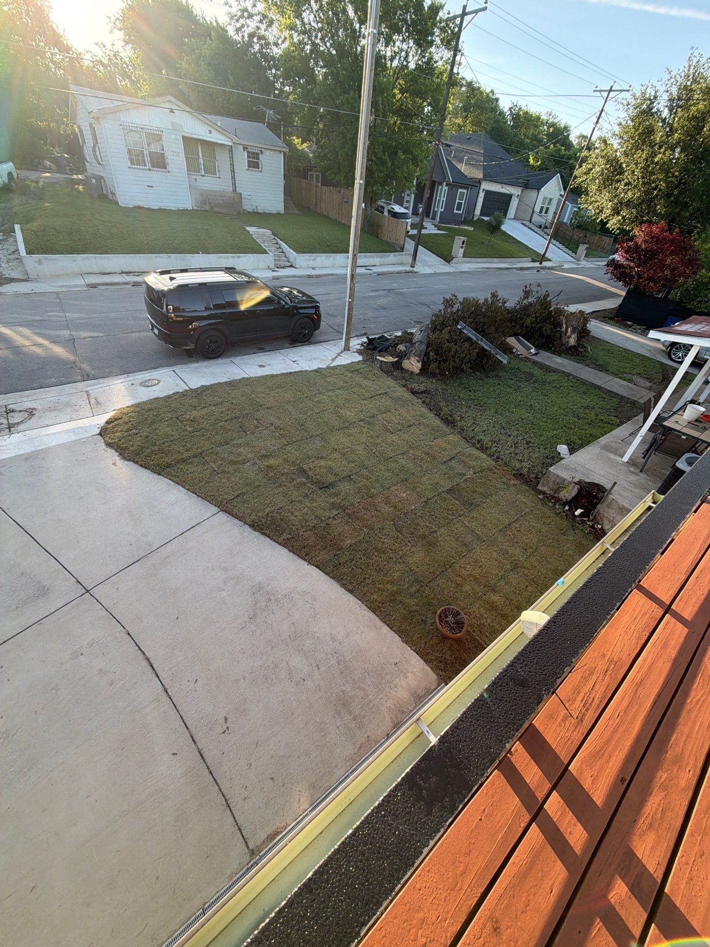 Front yard and driveway view with a parked black car on a quiet residential street.
