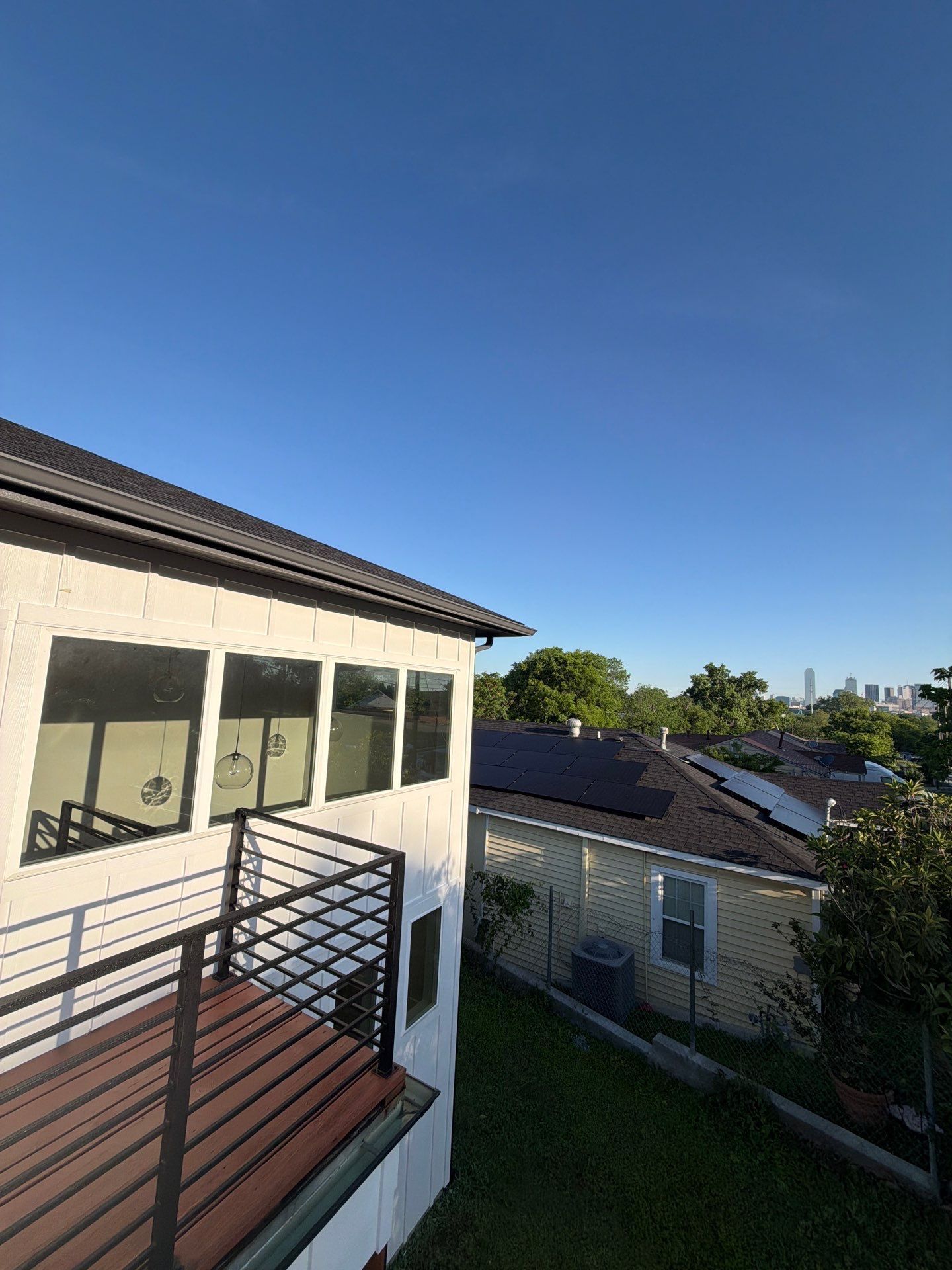 Balcony overlooking neighboring rooftops under a clear blue sky