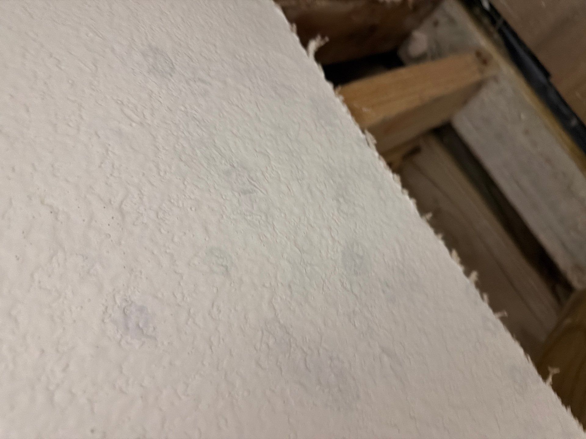 Close-up of a textured white surface with wooden beams in the background.