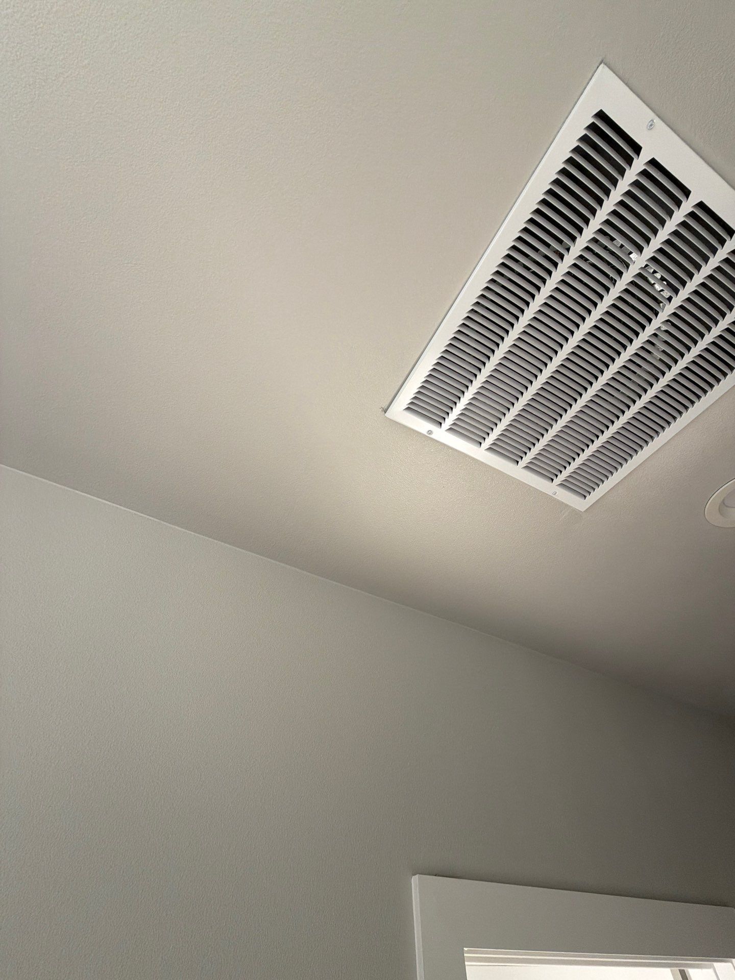 White ceiling with a rectangular air vent in the corner of a room
