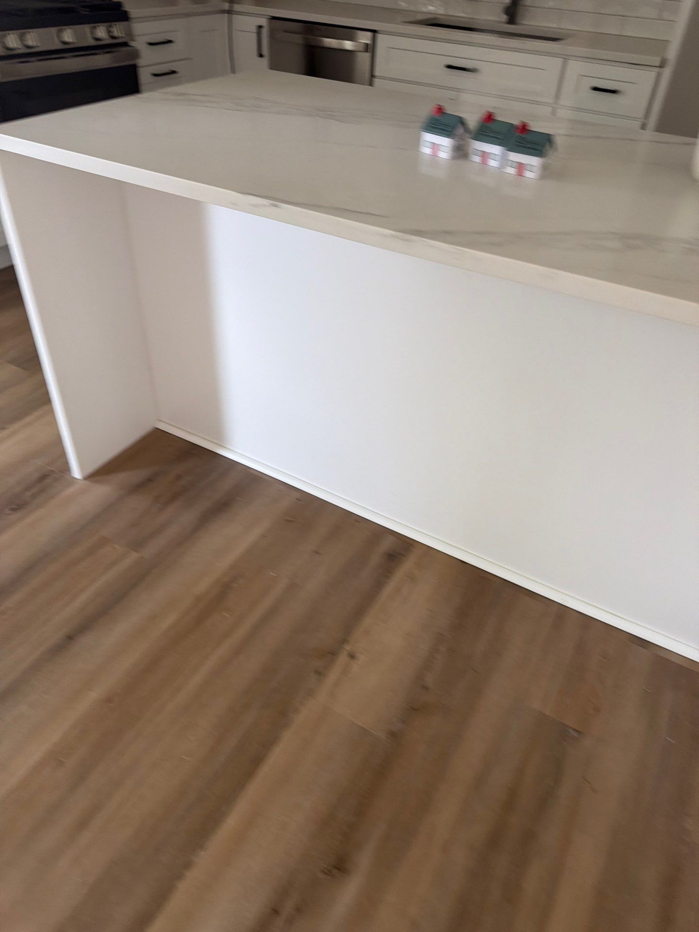 Modern kitchen with a light island, wood floor, and three water bottles on the countertop