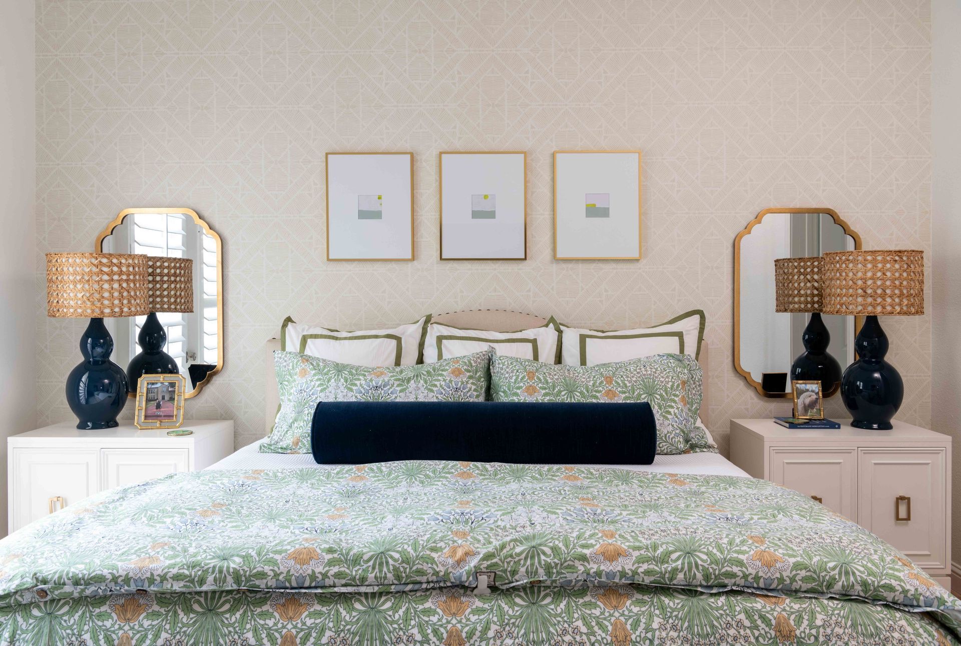 Coastal-style bedroom with a patterned bed, navy pillows, and matching bedside lamps on white nightstands