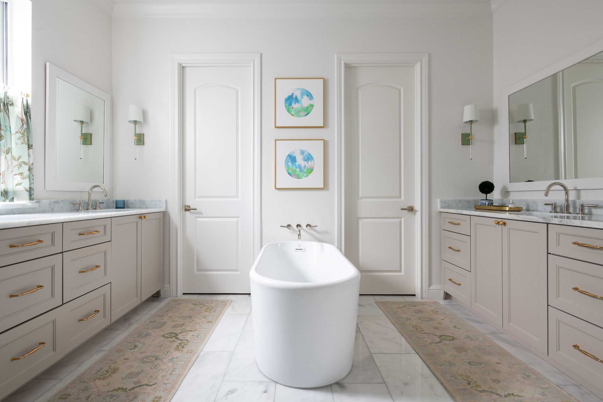 Bright white modern bathroom with double vanities, mirrors, and a freestanding tub centered between two doors