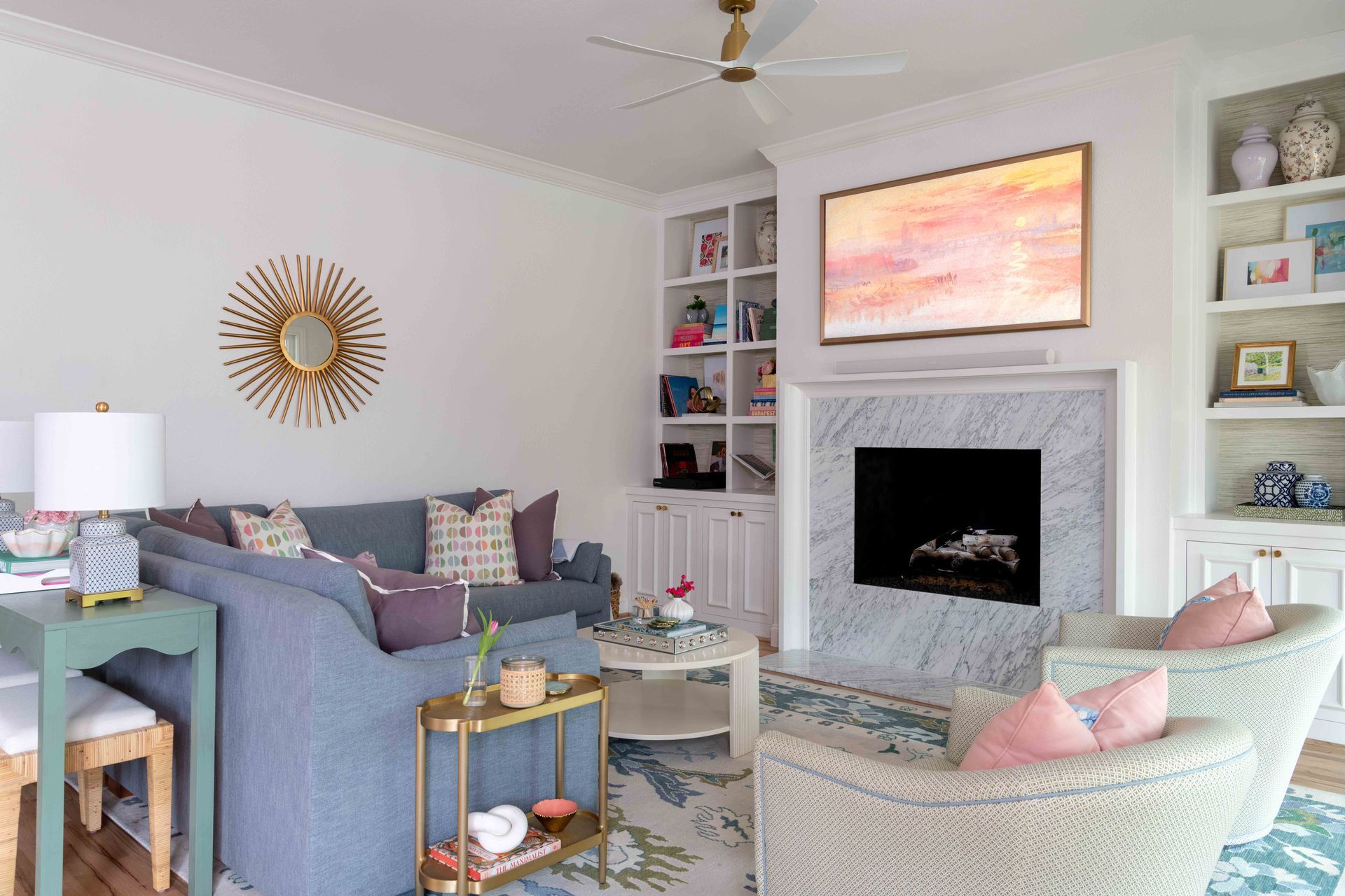 Bright living room with blue sofas, a fireplace, pink accents, and coastal decor