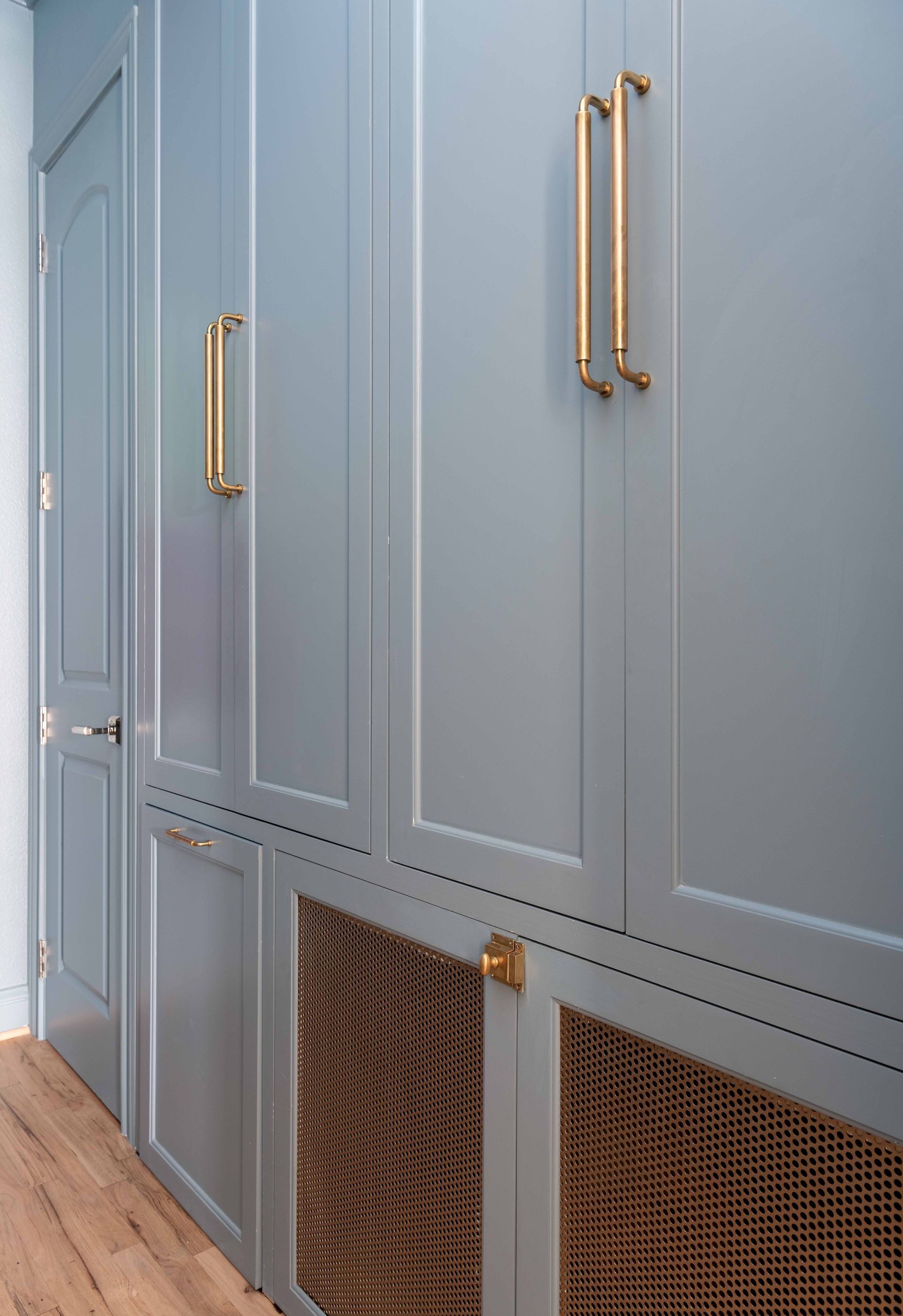 Blue built-in cabinets with gold handles and woven lower panels in a hallway