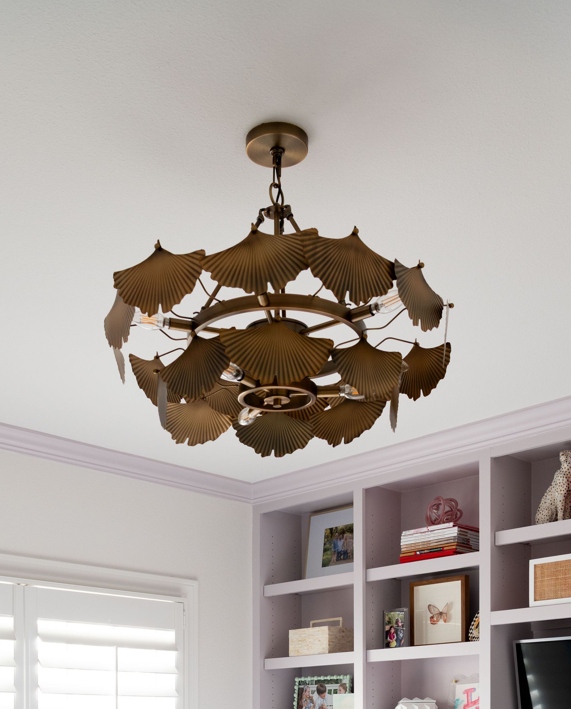 Ornate brass chandelier with leaf-like shades hanging from a white ceiling in a bright room