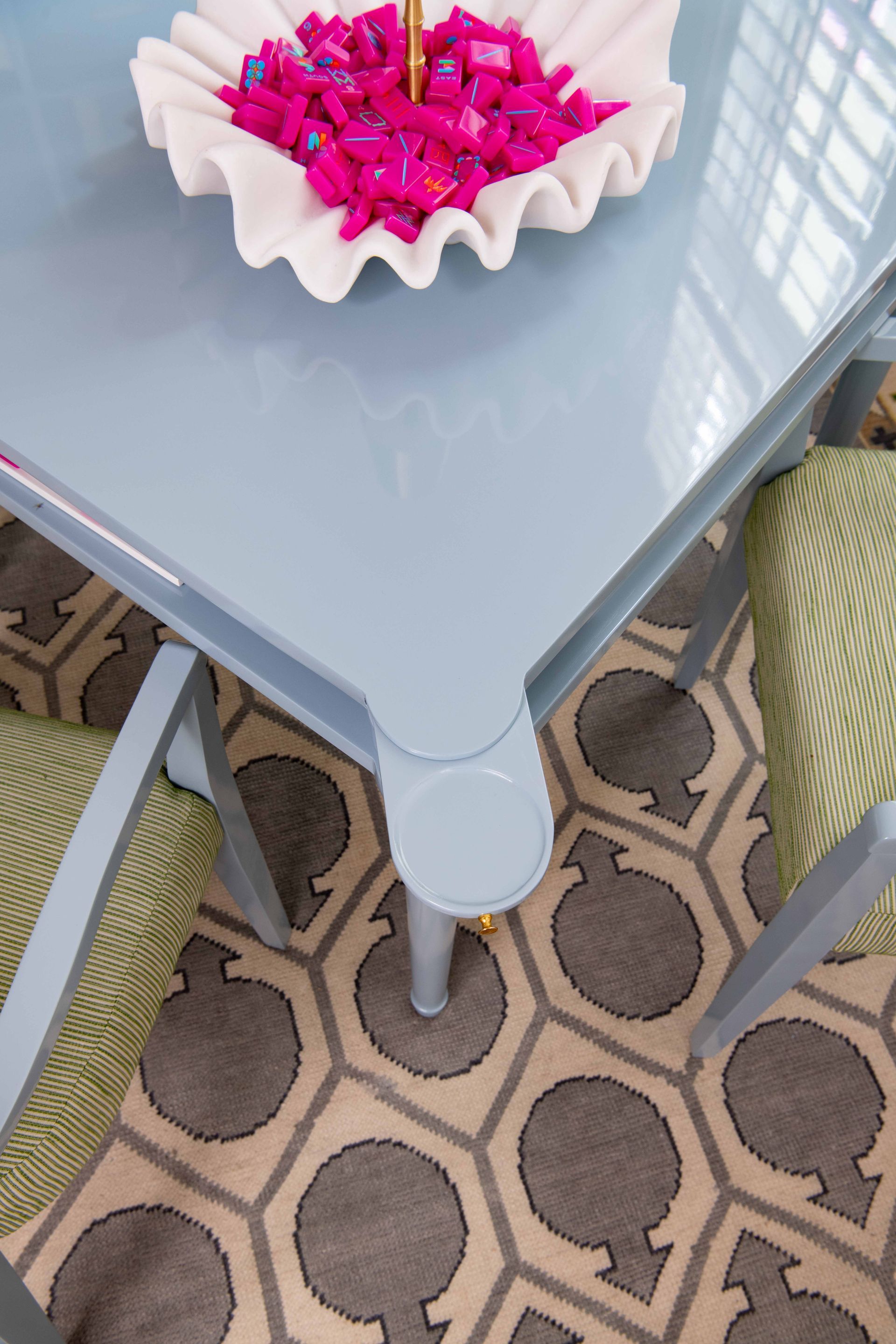 Glass patio table with a white tray of bright pink flowers over a patterned outdoor rug