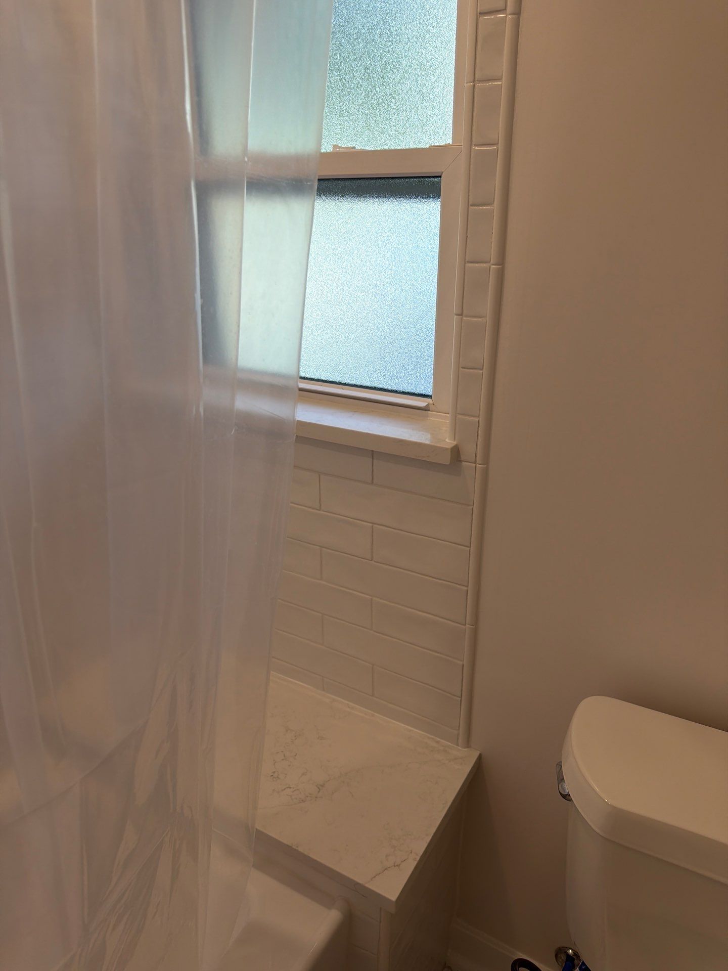 Small bathroom with shower, frosted window, and toilet visible.
