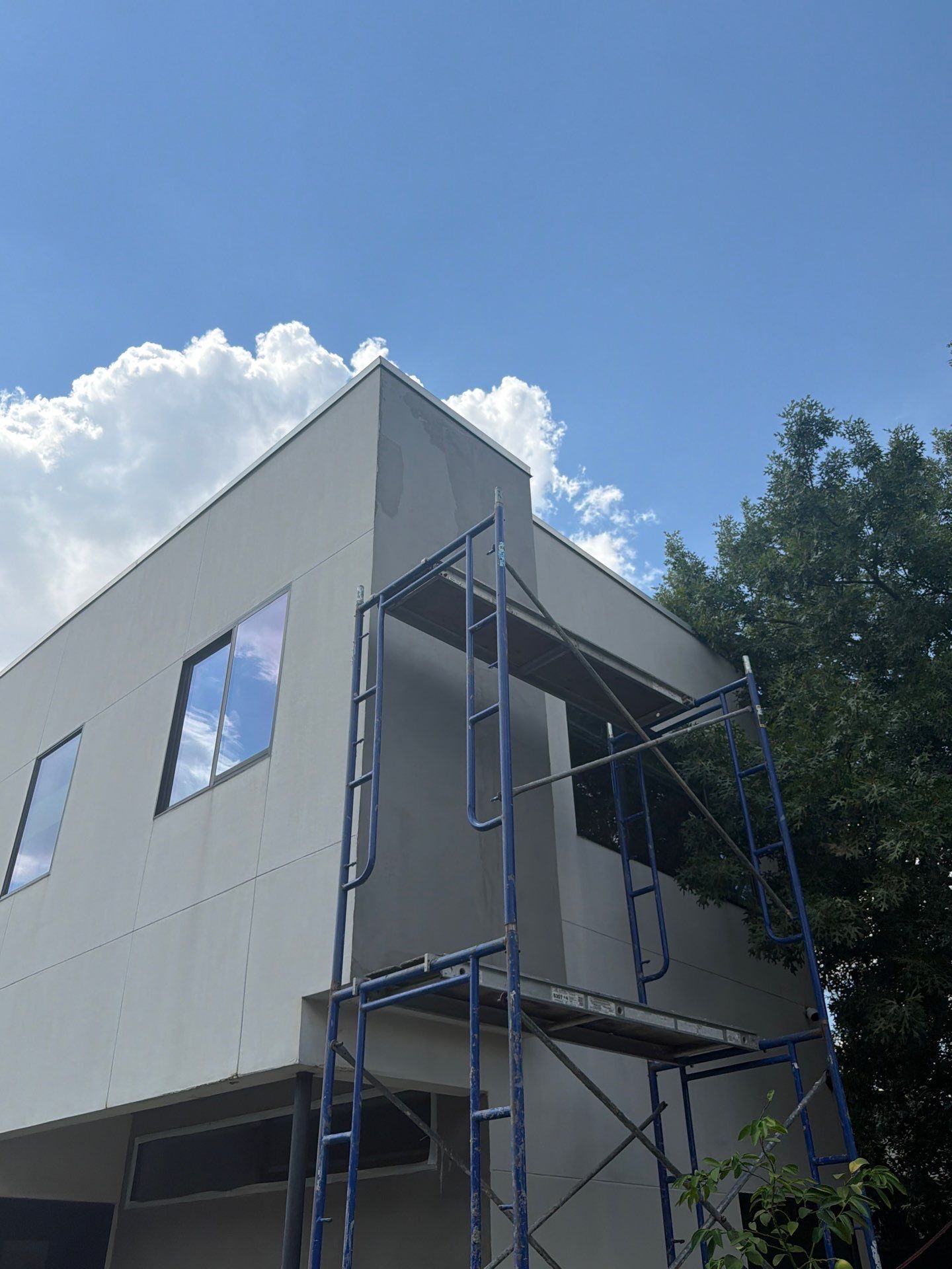 Empty living room with glossy wood floors, white walls, built-in shelves, large windows, and a fireplace.