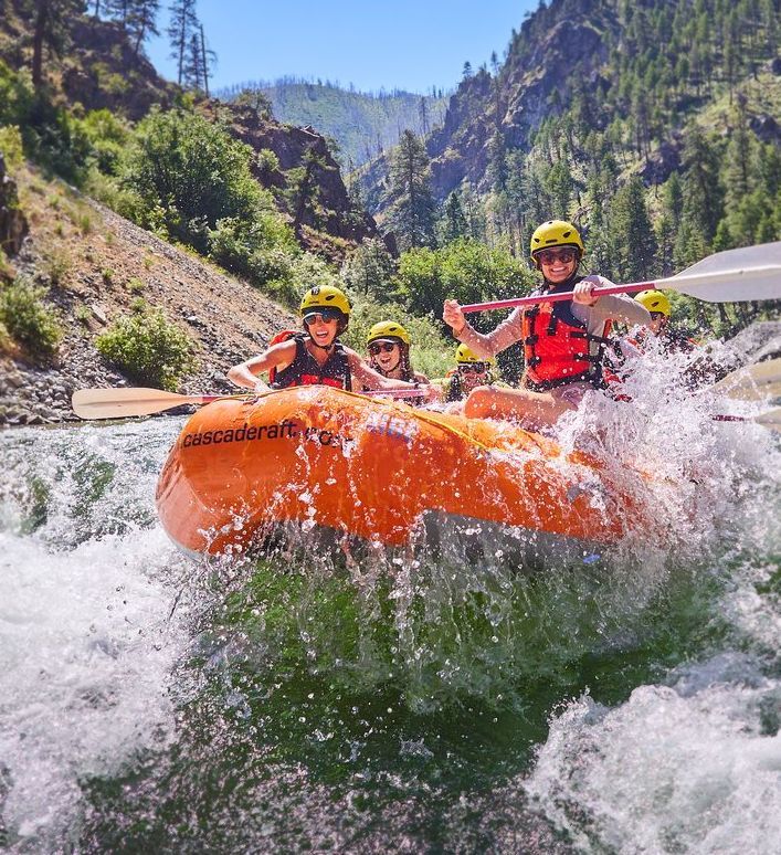 Rafters paddling an orange raft through a rocky canyon