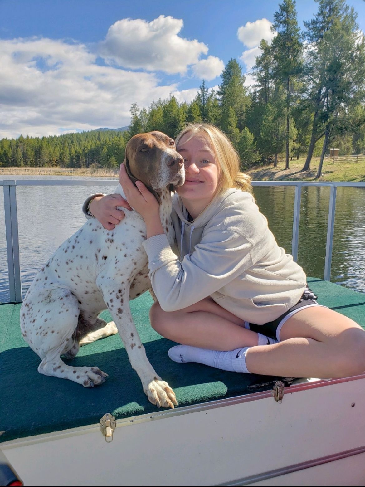 Staff member holding a dog beside a lake
