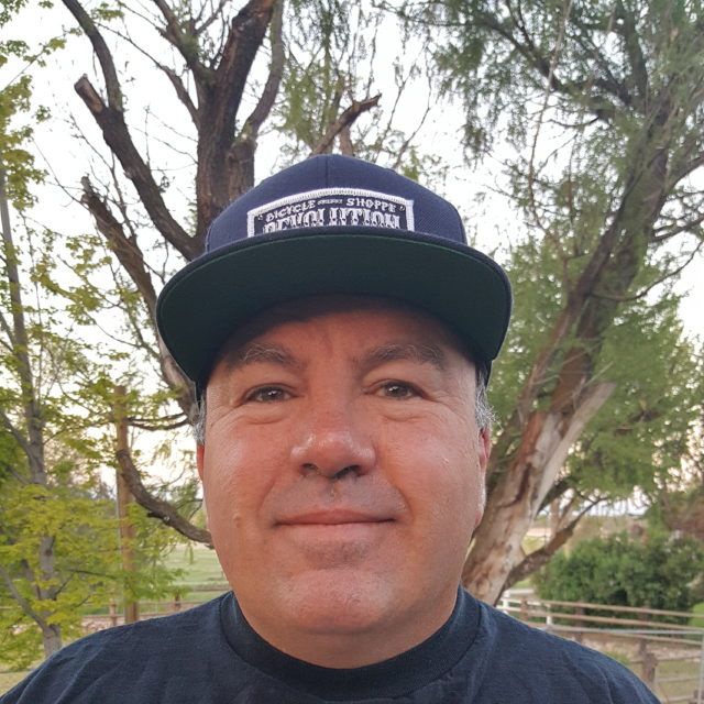 Staff member wearing a cap beneath a tree