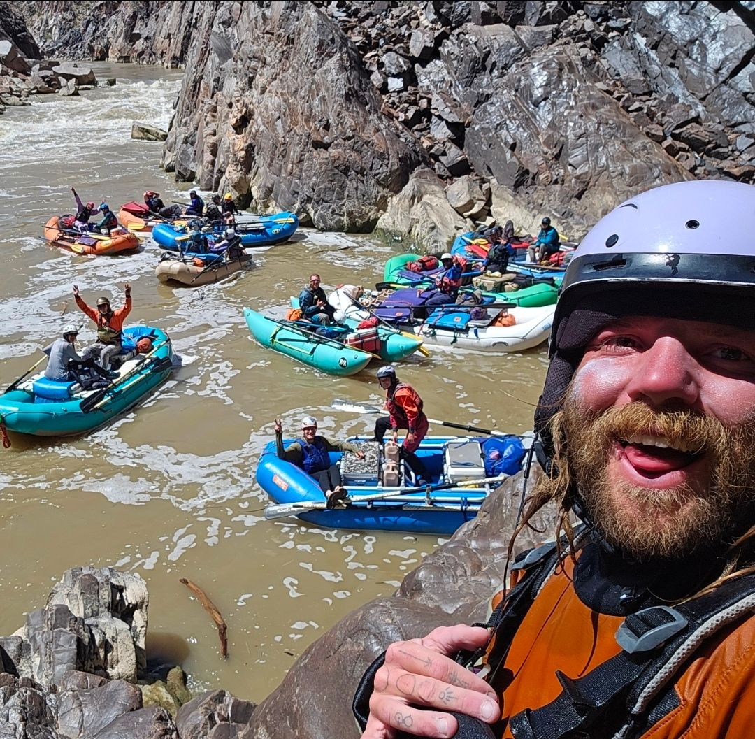 Helmeted paddler with kayaks gathered on a river behind