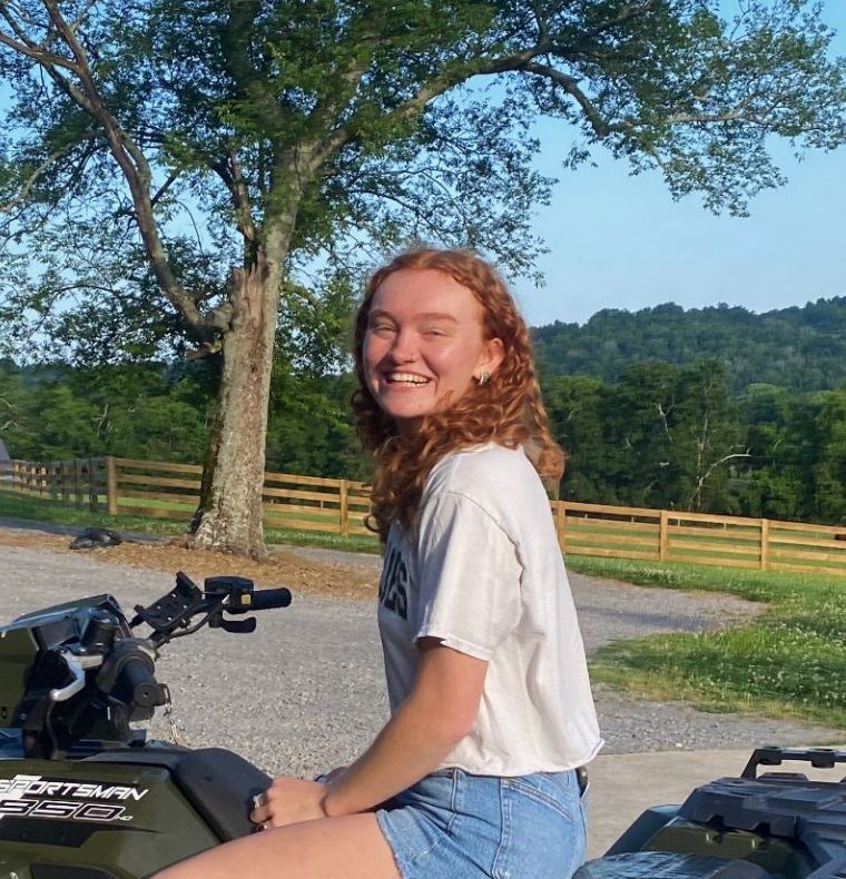 Staff member smiling beneath a leafy tree