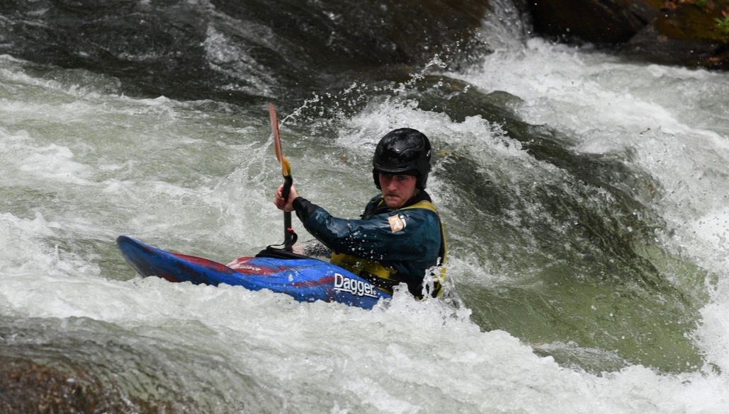 Kayaker paddling through a foaming rapid