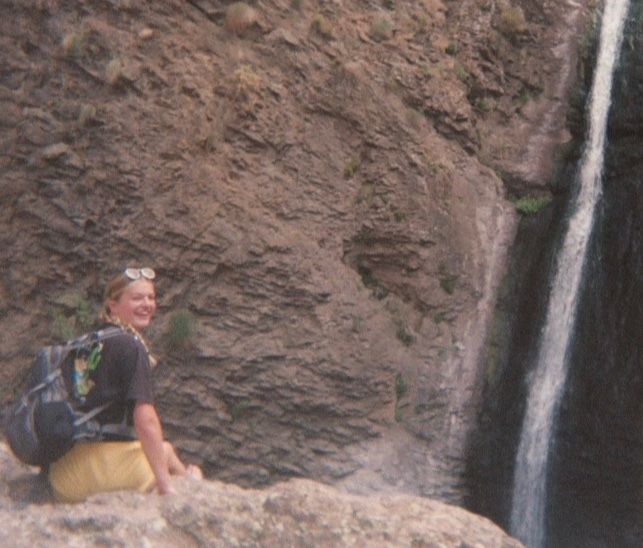Person beside a waterfall on a rocky cliff