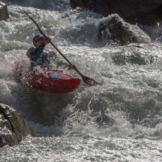 Kayaker paddling through whitewater rapids