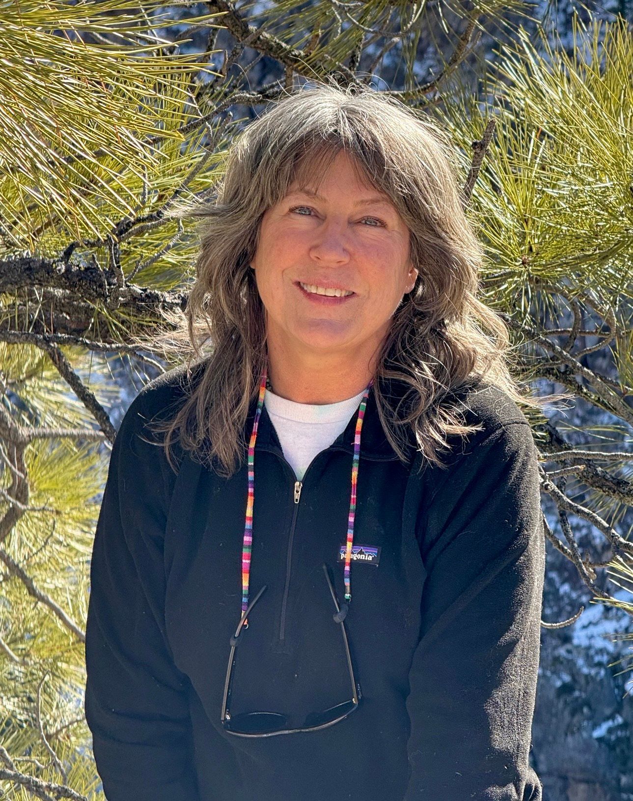Staff member smiling beneath leafy trees