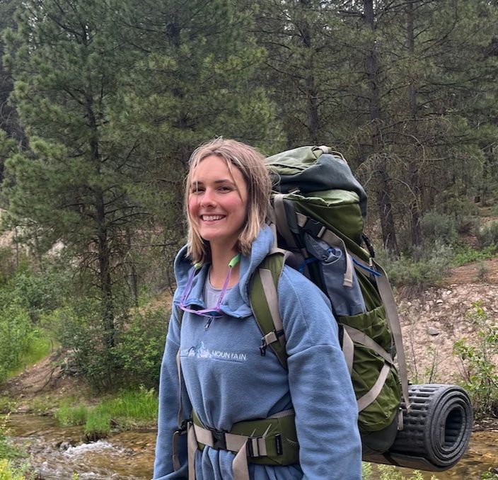 Hiker carrying a backpack on a green trail