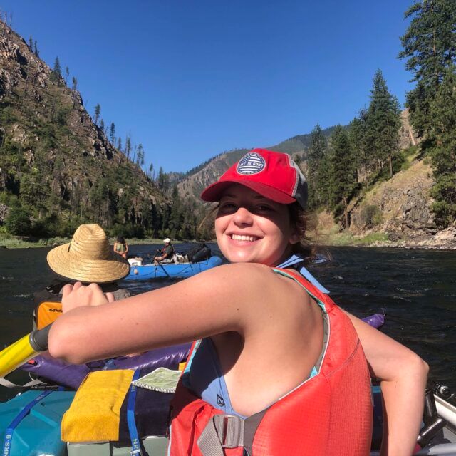 Staff member wearing a red helmet beside a river