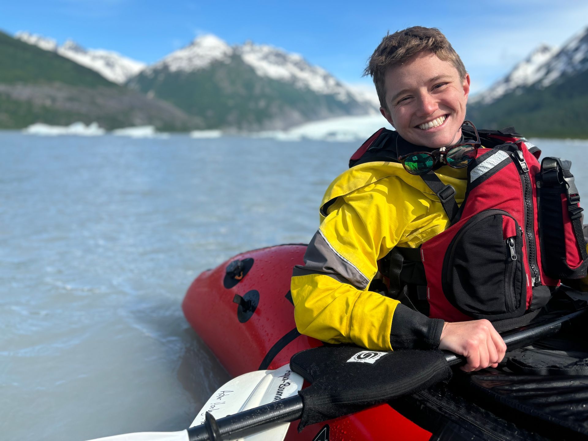 Paddler in a yellow jacket beside a mountain lake