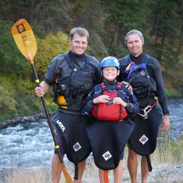 Three paddlers posing with a kayak paddle