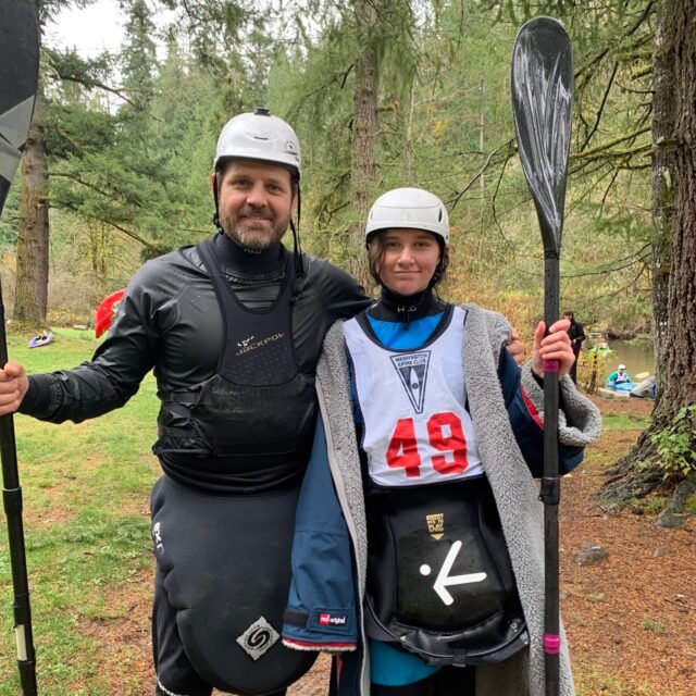 Two helmeted paddlers standing with kayak paddles