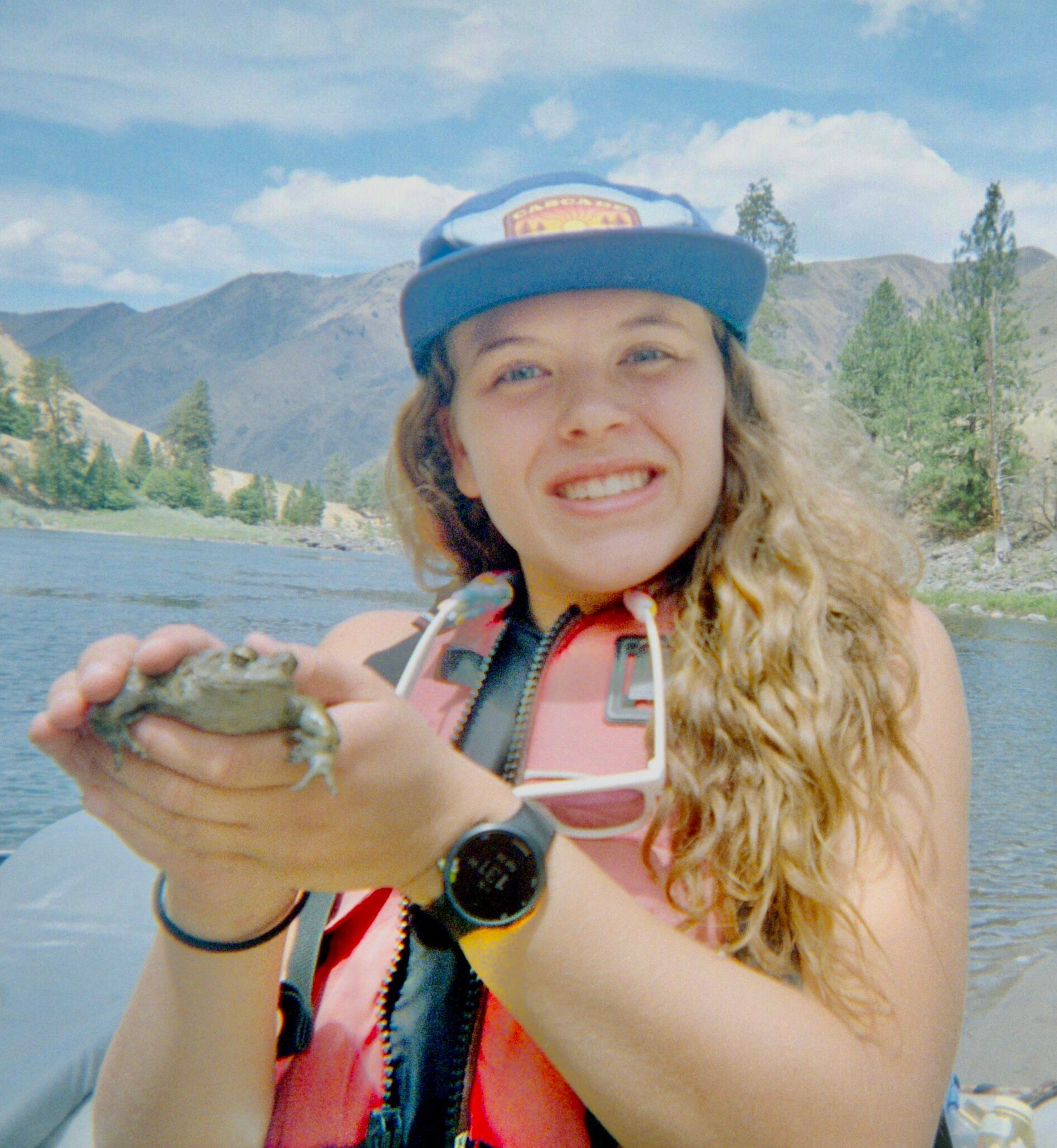 Staff member wearing a cap beside a river
