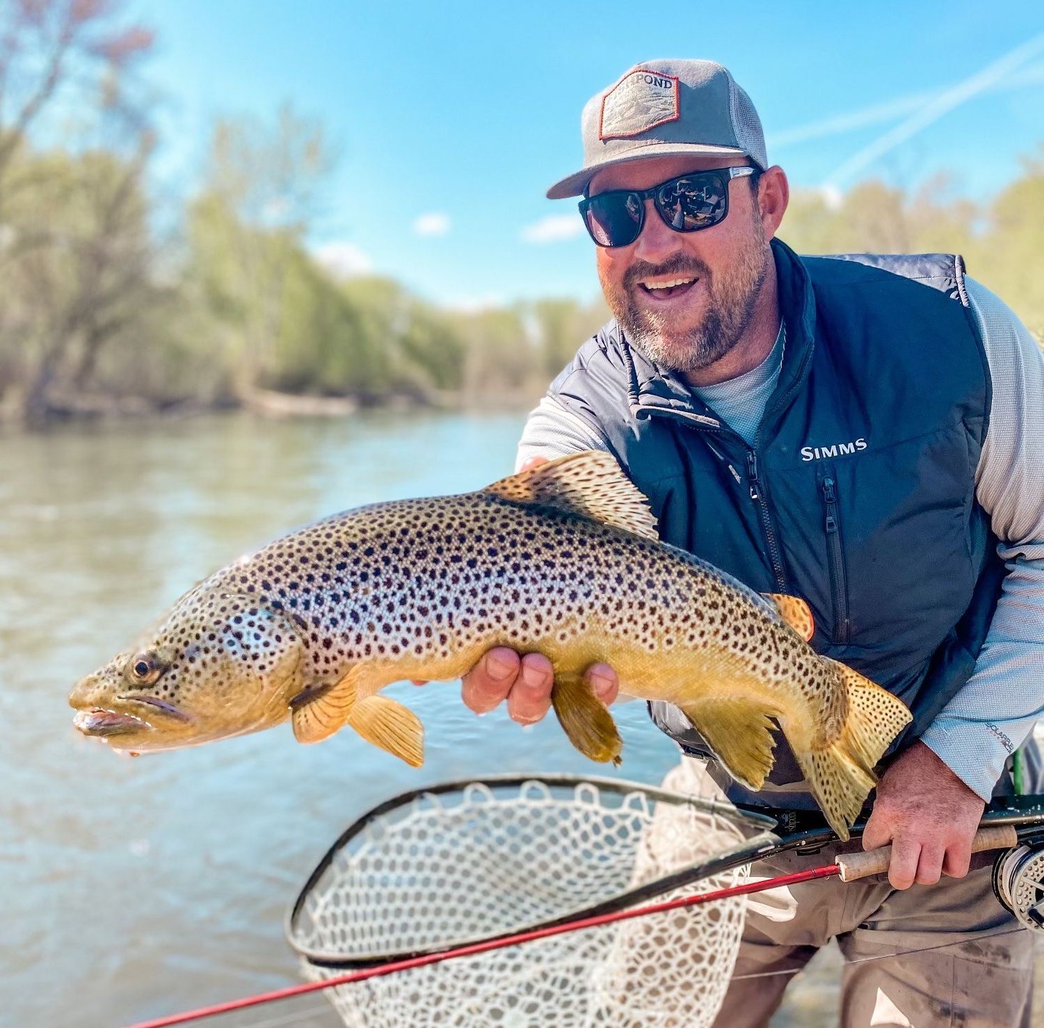 Angler holding a fish beside a river