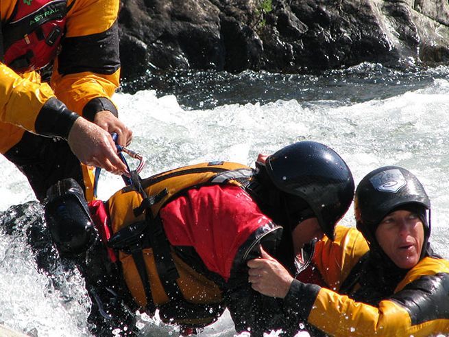 Two people rescuing someone in swiftwater