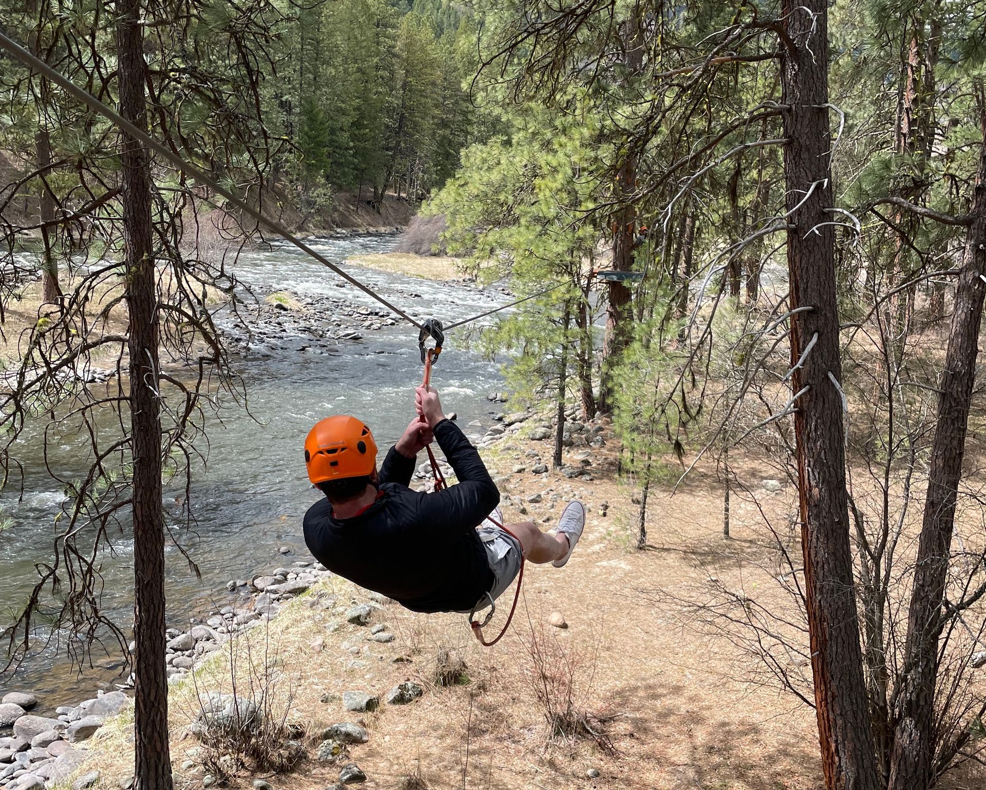 a person riding a zip line through the forest