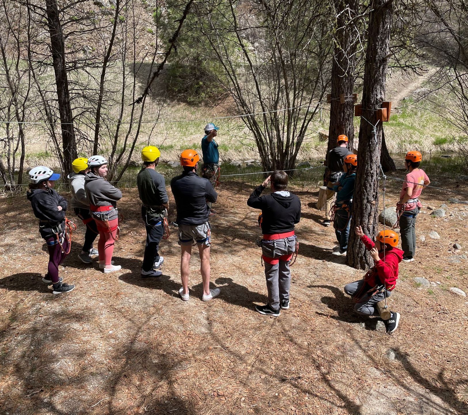 Group learning the safety and rules of ropes course in the forest with zip lines.