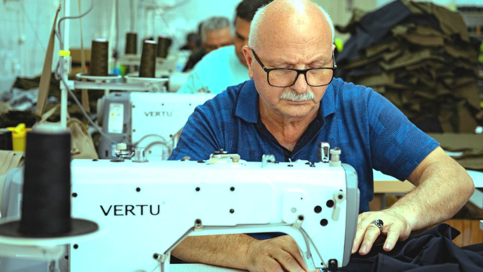 A man is using a sewing machine in a factory.