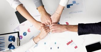 A group of people are putting their hands together on a table.