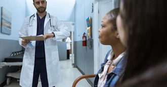 A doctor is talking to a patient in a hospital hallway.