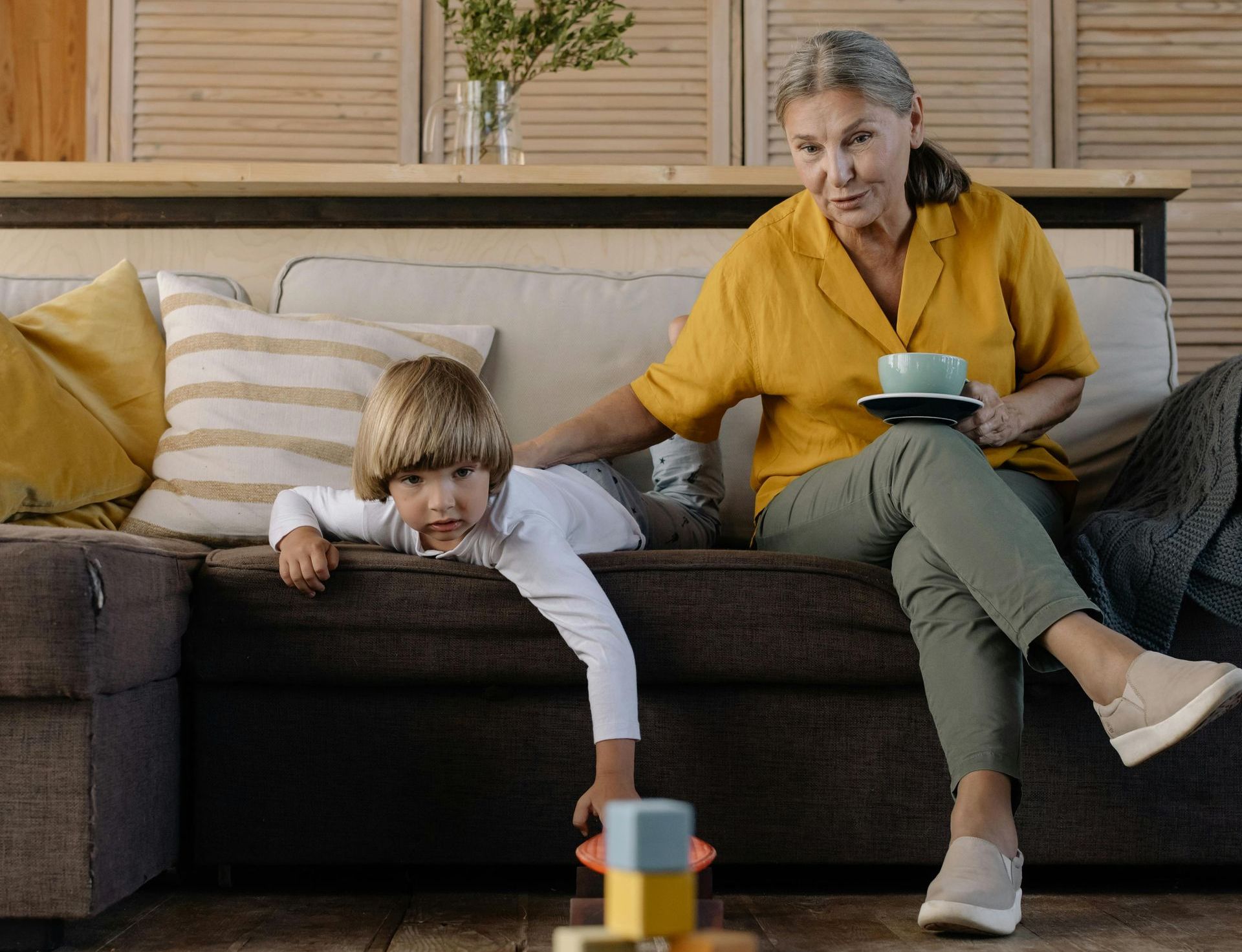 An elderly woman is sitting on a couch with a child.