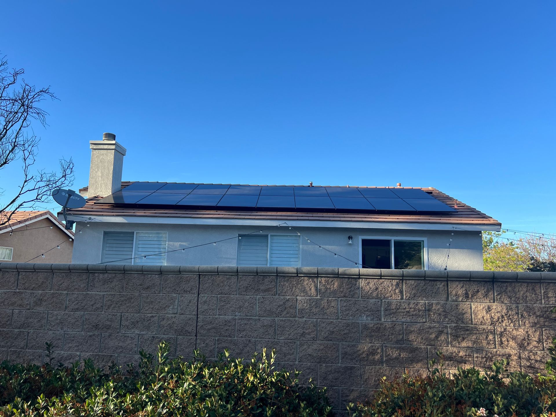 Two workers installing solar panel on a roof with a mountain backdrop.