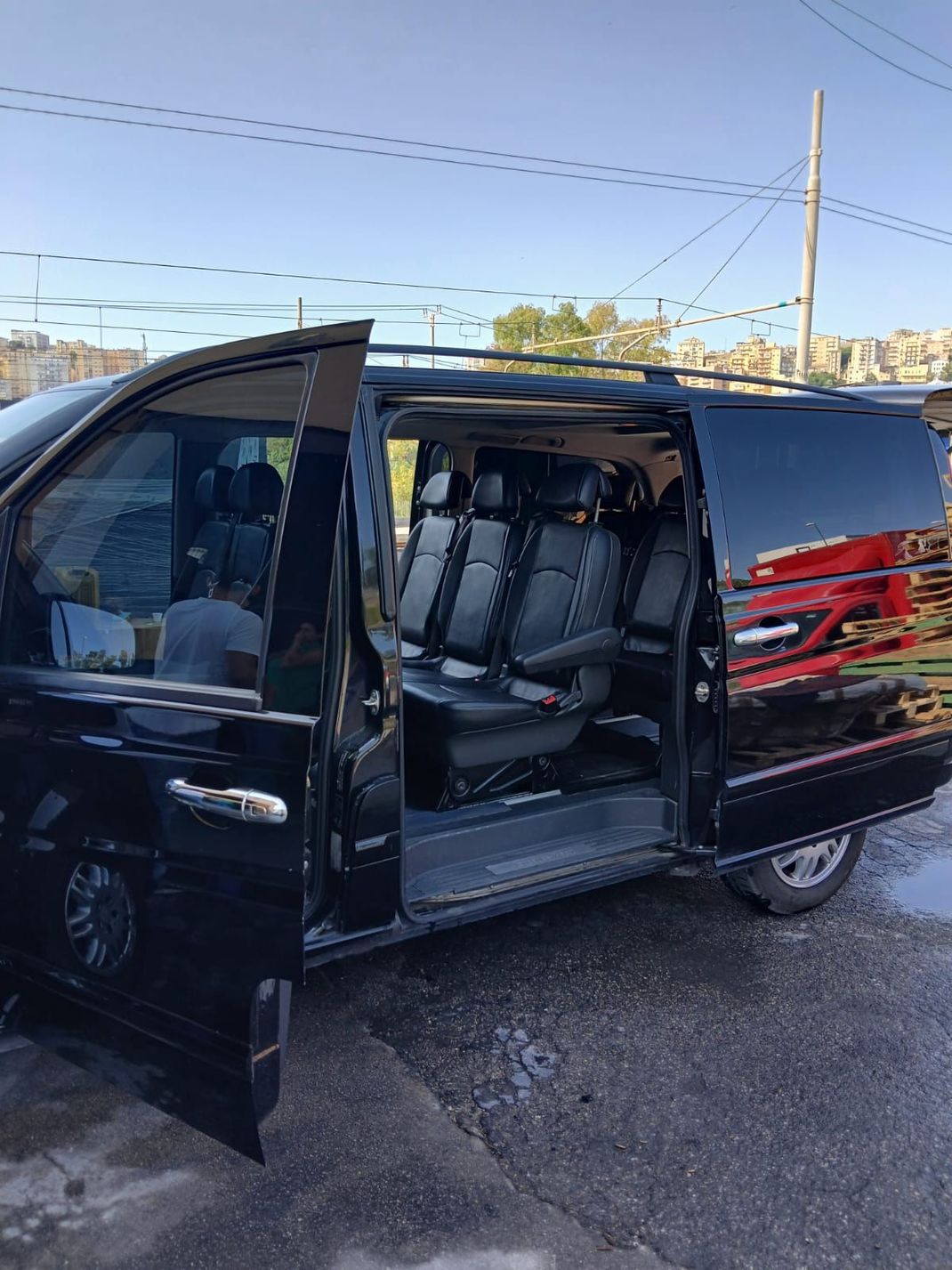 Un lussuoso minivan nero parcheggiato di notte davanti a un moderno edificio illuminato a giorno.