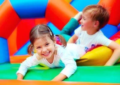 Two smiling children playing on a colorful inflatable bounce house