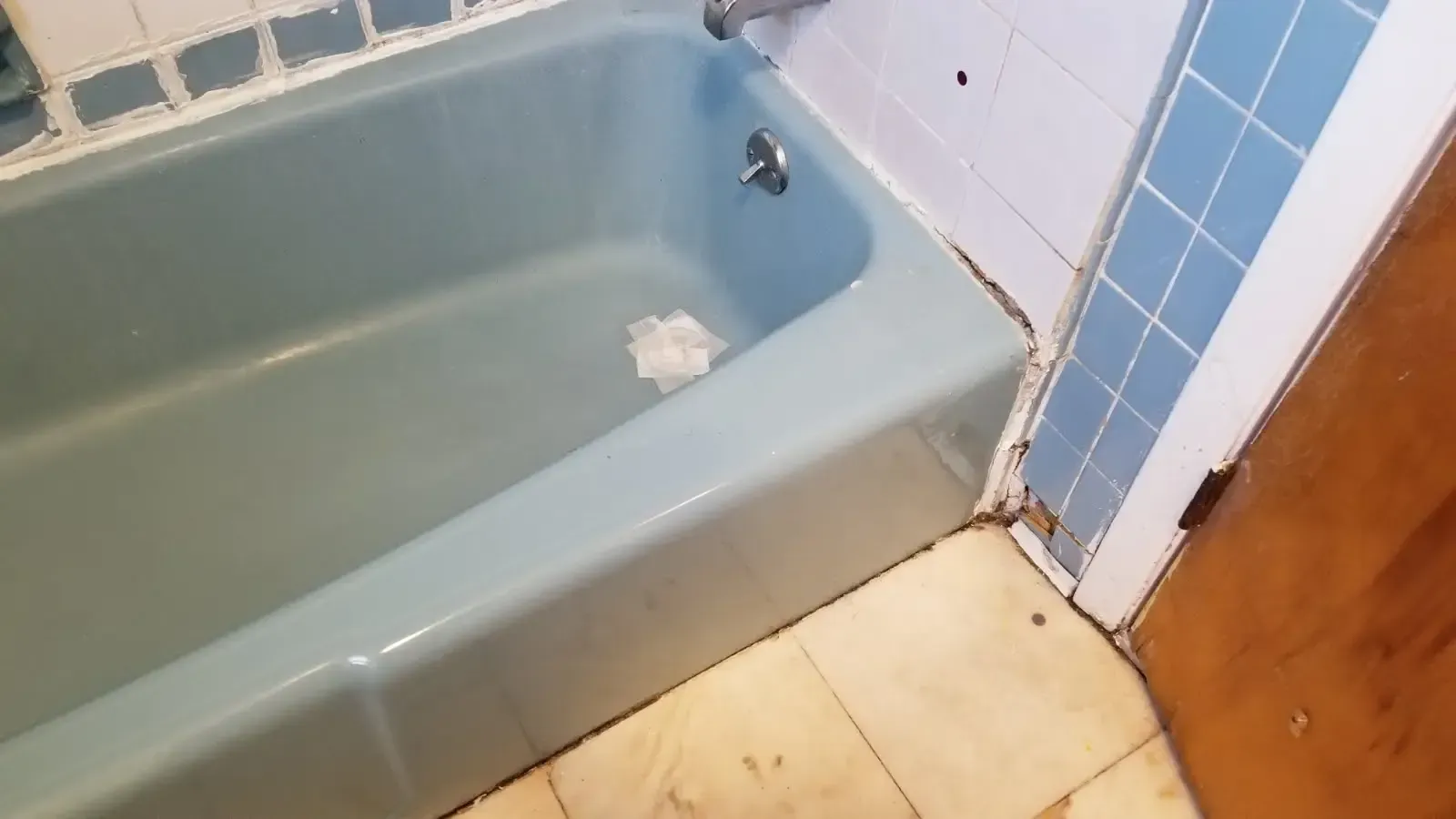 Bathroom with green bathtub, blue tile wall, and wooden floor beside it