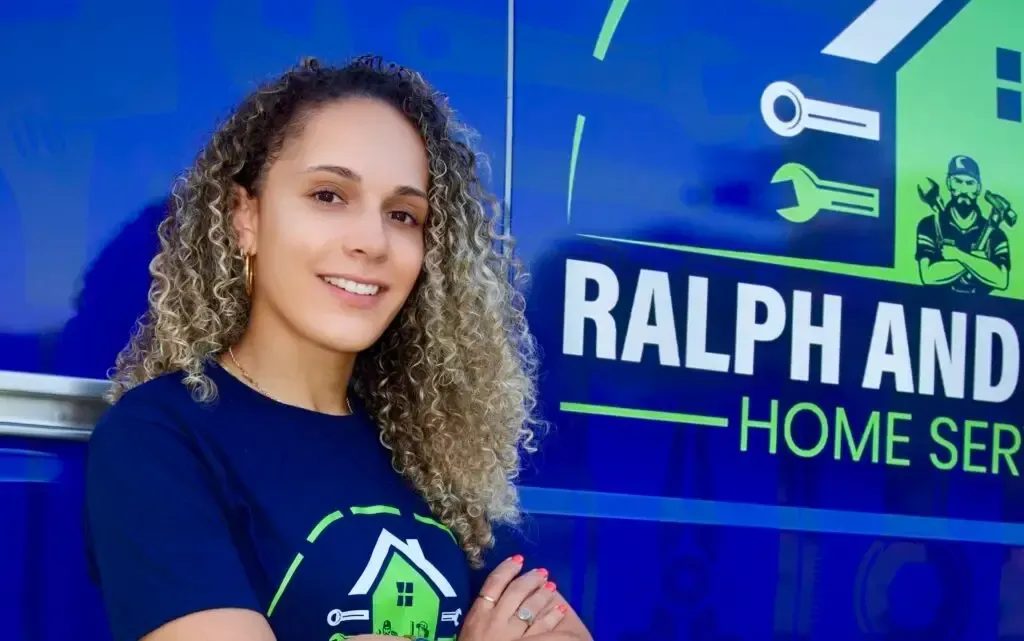 Woman in a blue shirt standing by a Ralph and Home Services sign