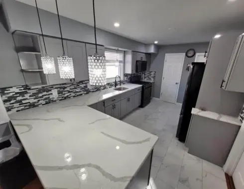 Modern gray-and-white kitchen with marble island, pendant lights, and stainless appliances