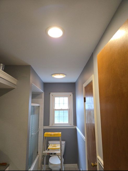 Narrow hallway with recessed lights, a window, closet shelves, and a step ladder on the floor.