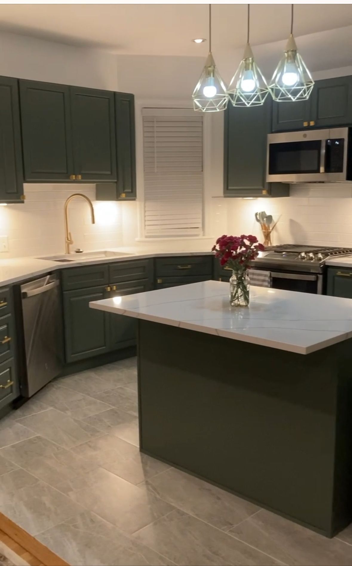 Modern kitchen with dark cabinets, white island, stainless appliances, and pendant lights