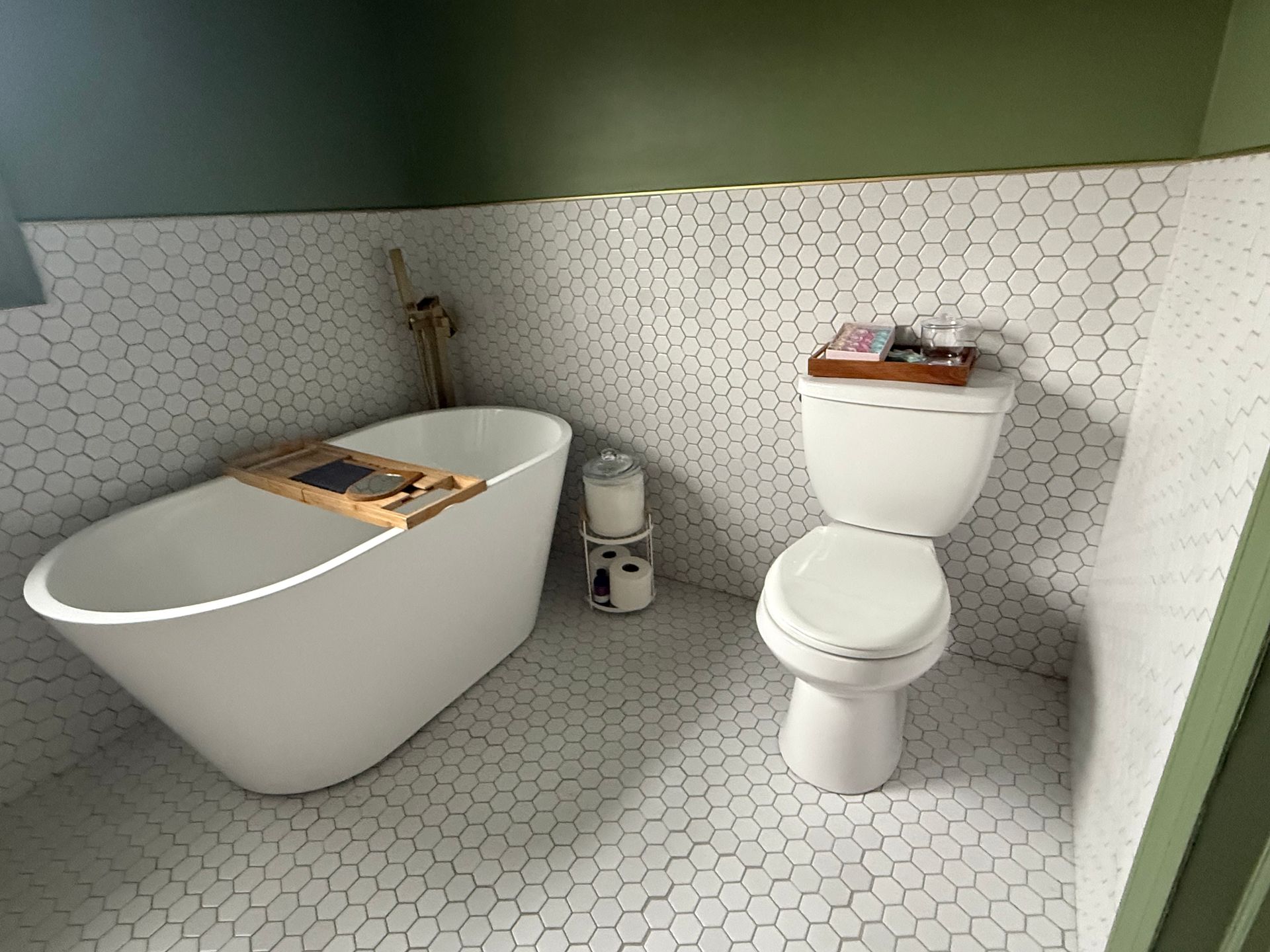 Modern bathroom with a freestanding tub, toilet, and hexagon tile walls and floor.