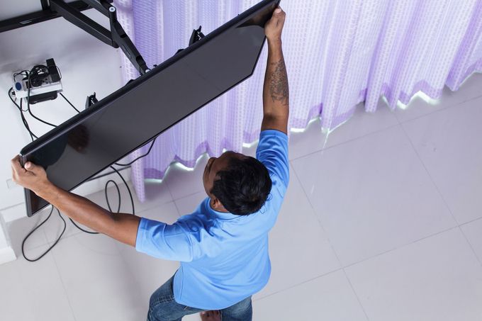 Person adjusting a large black screen or panel on a white floor, viewed from above