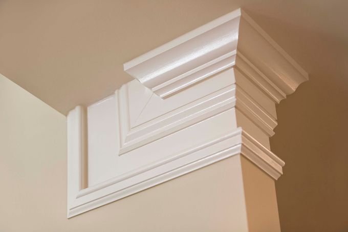 White decorative crown molding on a beige interior corner near the ceiling