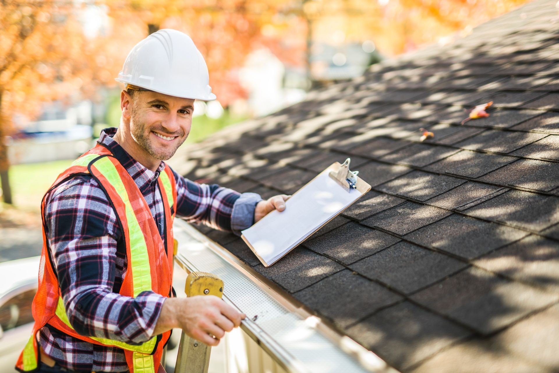 Roof inspector checking asphalt shingles with clipboard during autumn safety inspection. Roof inspector checking asphalt shingles with clipboard during autumn safety inspection.